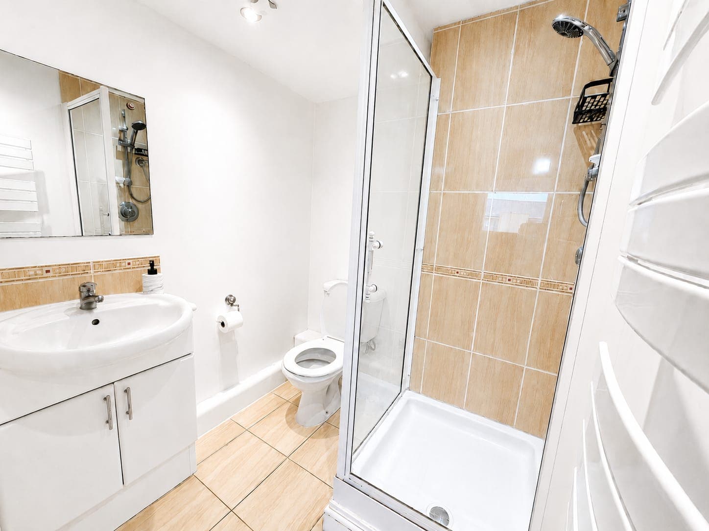Modern en-suite bathroom featuring a spacious walk-in shower with rainfall head, contemporary vanity unit with mirror, and warm wood-effect tiling throughout.